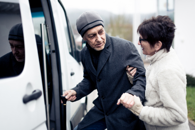 woman helping elderly man in boarding the van